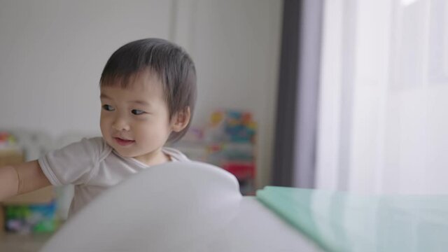 Asian toddler playing with her toys and slider at home, child support cnas care, learning by playing, practical home school experience, kids emotion during the day, joyful smiling child playing alone