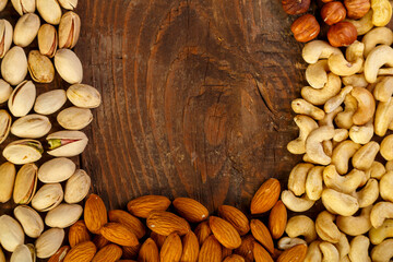 Frame of scattered assorted nuts on a wooden table. Copy space.