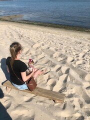 a girl with a dog on the beach looking at the water