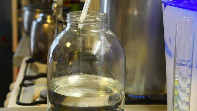 Distilling moonshine from yeast brew. Moonshiner prepares strong alcohol at home. The moonshiner workflow. 