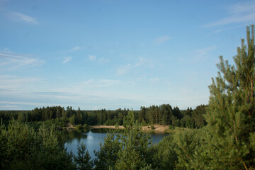 Summer landscape with a beautiful lake with fir trees and forested mountains against a cloudy sky