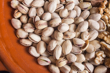 A portion of pistachios in a clay pot. Healthy snacks and food.