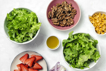 Salad with lettuce, strawberries, red onion, corn; olive oil and walnuts