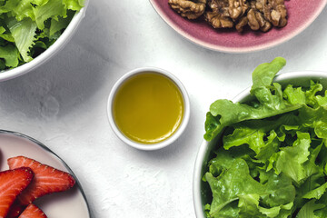 Salad with lettuce, strawberries, red onion, corn; olive oil and walnuts