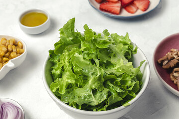Salad with lettuce, strawberries, red onion, corn; olive oil and walnuts