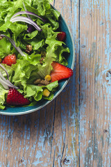 Salad with lettuce, strawberries, red onion, corn; olive oil and walnuts
