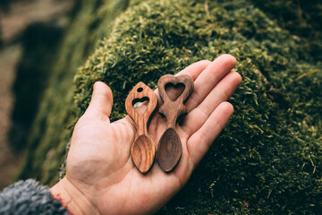 Traditional wooden love spoons from Wales in hand on mossy background.	