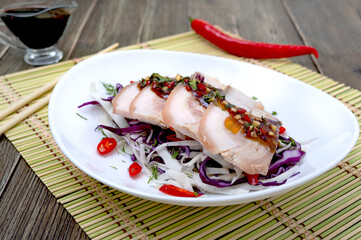Pork belly with cabbage salad in a white bowl on a wooden background. Chinese cuisine.