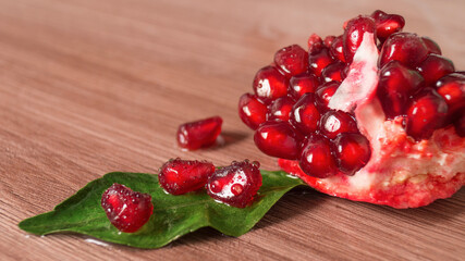 Ripe juicy red pomegranate slices on a wooden background