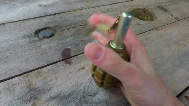 the hand holds the fuse of the hand grenade and releases it