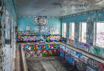Abandoned Soviet time swimming pool and sports hall complex. Colorful graffiti paintings on the walls. Urban exploration.
