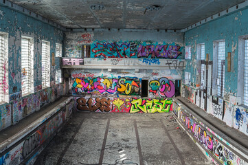 Abandoned Soviet time swimming pool and sports hall complex. Colorful graffiti paintings on the walls. Urban exploration.