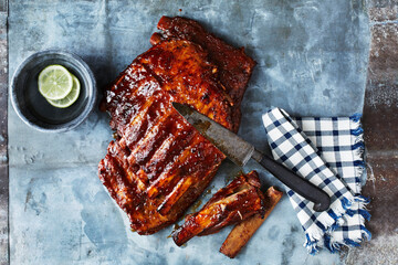 Still life with BBQ spare ribs and kitchen knife, overhead view