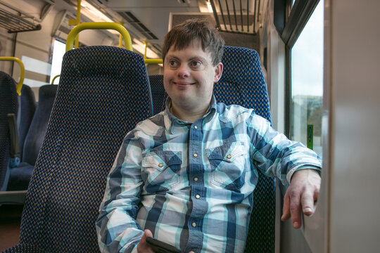Man with down syndrome with cell phone on train
