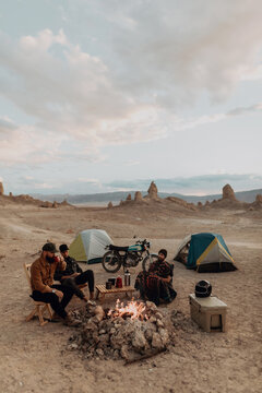 Motorcyclist road trippers around camp fire, Trona Pinnacles, California, US