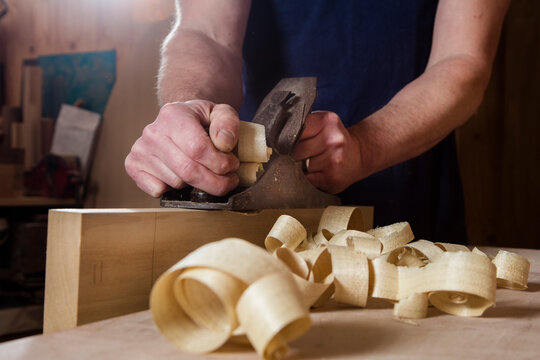 Craftsman using wood plane in workshop