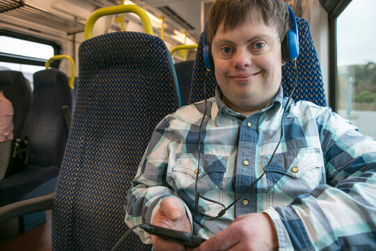 Man with down syndrome with using headphones and cell phone on train