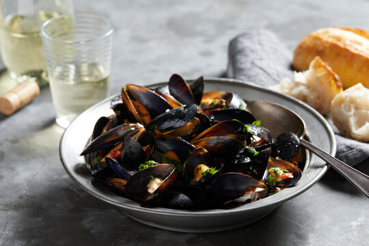 Bowl of garlic mussels with glass of white wine
