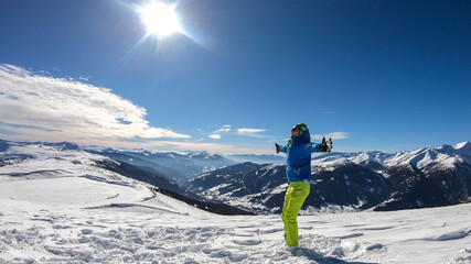 A young man wearing a blue skiing jacket doing yoga at the top of Katschberg, ski resort in...