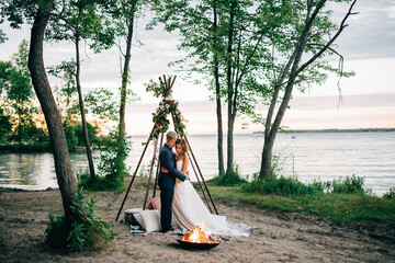 Bride and groom looking down at lakeside campfire, Lake Ontario, Toronto, Canada