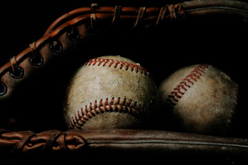 Dark and moody baseball still life with ball and old used glove for sports nostalgia.