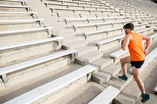 Young male runner running up stadium stairway