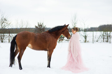 Eine hübsche Frau, sieht aus wie Aschenputtel steht mit Rosa Tüll Kleid  im Schnee und streichelt...
