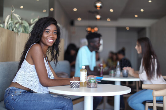 Woman using smartphone in ice cream parlour, customers in background