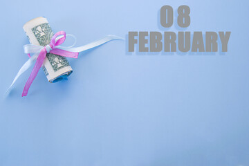 calendar date on blue background with rolled up dollar bills pinned by blue and pink ribbon with copy space. February 8 is the eighth day of the month