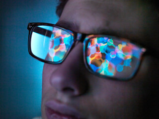 Biotechnology research, computer screen reflection in spectacles of new molecular formula in laboratory, close up of face