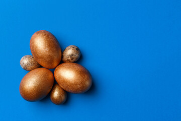 Golden modern easter eggs on a blue background. Easter concept. Isolated.