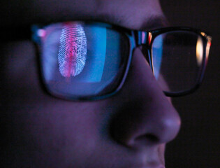 Cyber Security, reflection in spectacles  of access information being scanned on computer screen, close up of face