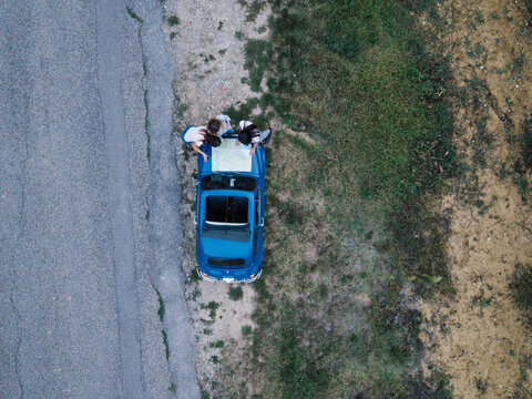 Overhead view of friends reading route map on car bonnet by roadside
