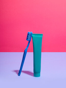 Toothbrush and toothpaste against pink and lilac background