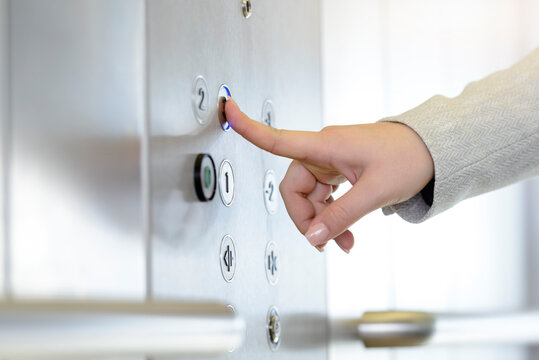 Woman Pressing Button Inside Elevator