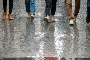Young people walking on rainy cobblestone pavement