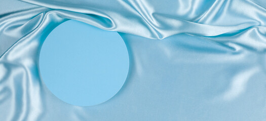 Geometric round platform podium on light blue silk satin background. Blank minimal cylinder form...