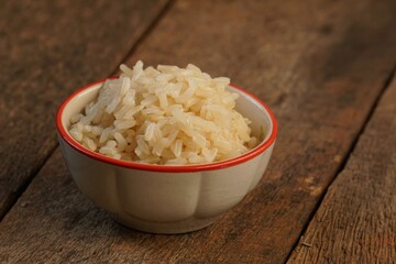 Cooked brown rice in the bowl was placed on the wooden floor.