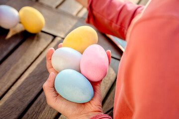 Girl with a handful of dyed easter eggs at table, cropped over shoulder view