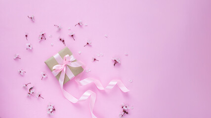 Cherry blossom and gift box with pink ribbon on pink background. Web banner image with copy space
