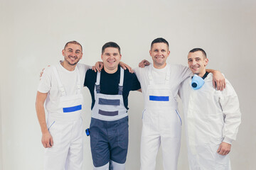 A team of construction workers, four people, men performing construction and repair work looking into the camera