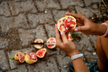Fototapeta na wymiar Top view of pomegranate fruit with red ripe seeds in woman's hands