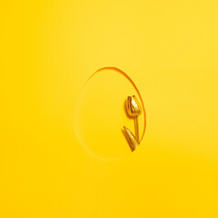 golden tulip in the frame of easter egg on sunny summer yellow background. minimal flat lay. abstract art