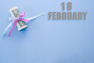 calendar date on blue background with rolled up dollar bills pinned by blue and pink ribbon with...