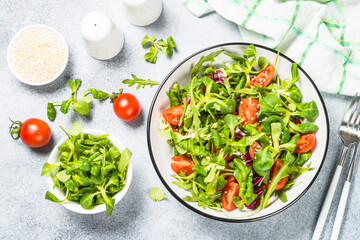 Healthy salad with arugula, lamb and tomatoes. Top view at white table.