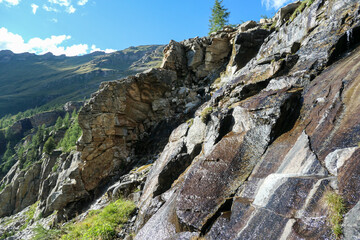 A close up view on steep and high mountain chain in Heiligenblut region, Austria. There are few small waterfall along the slopes. The slopes are overgrown with moss and grass. High Alpine landscape