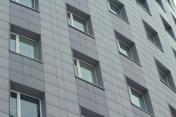 Plastic windows in a modern gray tiled brick high-rise house. Bottom view. Stock photo modern urban development for web and print.