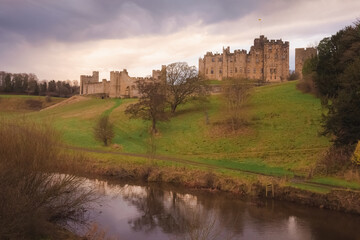 Naklejka na ściany i meble Dramatic and colourful sunset or sunrise clouds above the River Aln and Alnwick Castle, England.