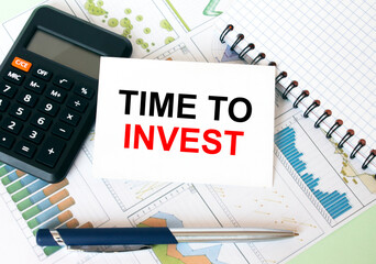 Business card with text Time To Invest laying on financial graphs