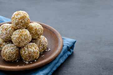 home made nutritional energy balls consisting of nuts, oatmeal, honey, dried fruits on a clay plate on a dark black slate background with a blue towel with place for text. healthy snack